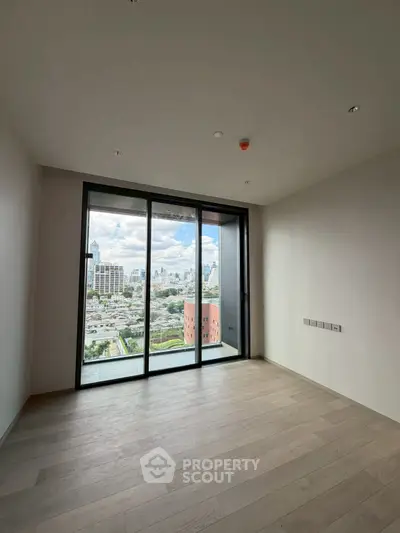 Spacious empty room with large windows offering stunning city views in modern apartment.