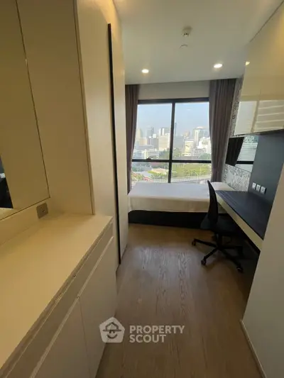 Modern bedroom with city view, sleek furnishings, and ample natural light.