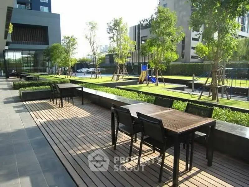 Modern outdoor seating area with lush greenery and sleek design in a contemporary residential complex.