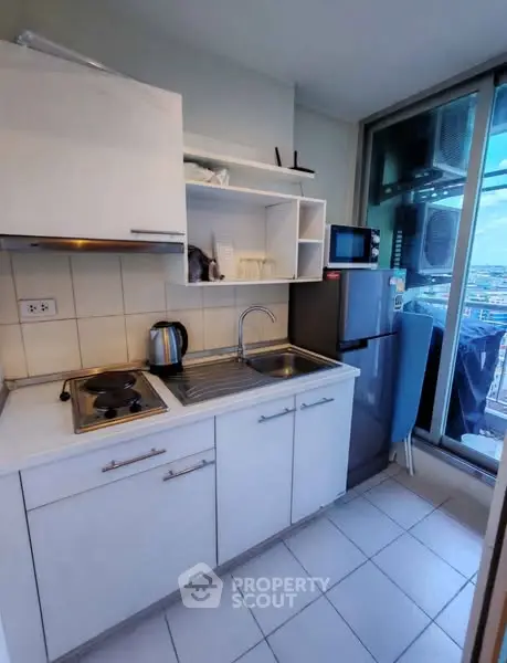 Compact kitchen with modern appliances and city view from window.