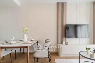 Modern living room with elegant dining area and wall-mounted TV, featuring stylish decor and wooden flooring.