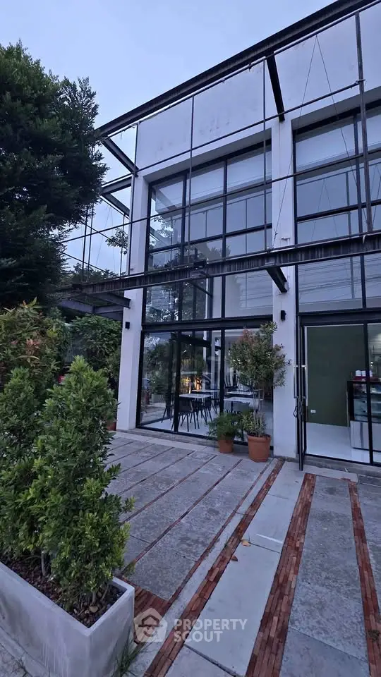 Modern industrial-style building with large glass windows and lush greenery