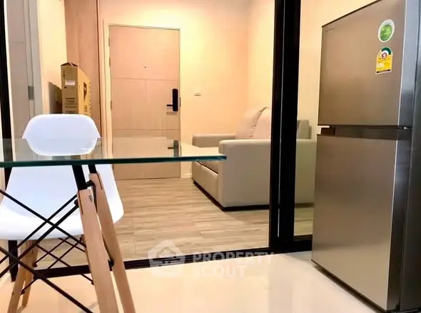 Modern apartment interior with glass dining table and stainless steel fridge