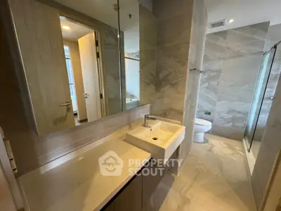 Modern bathroom with sleek design, featuring a spacious vanity and glass-enclosed shower.