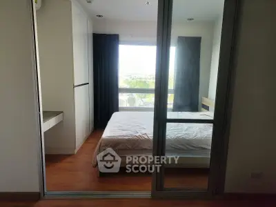 Modern bedroom with large window and wooden flooring in a stylish apartment.