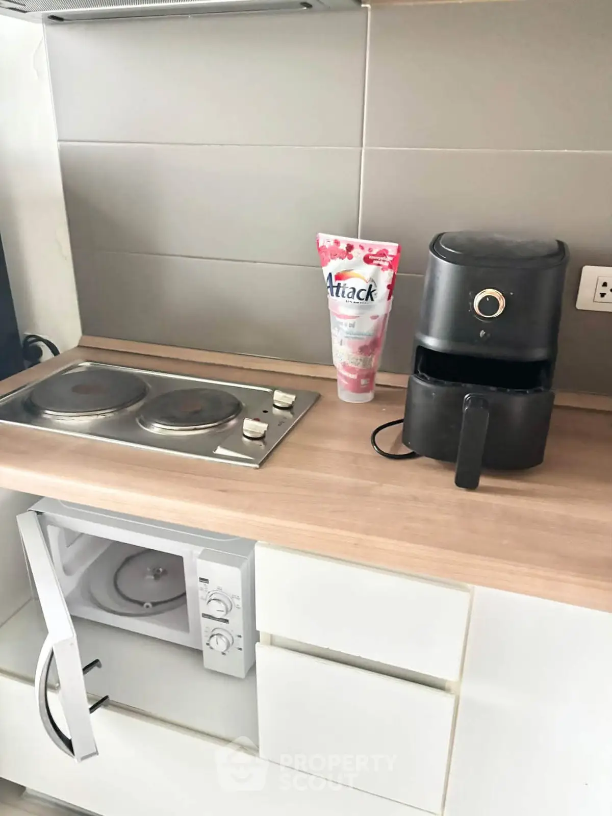 Modern kitchen with electric stove, microwave, and air fryer on wooden countertop.
