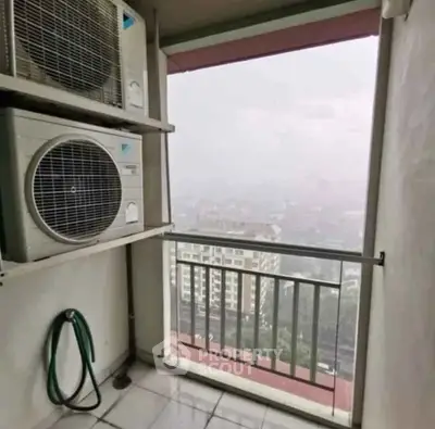 High-rise balcony with air conditioning units and city view on a misty day.
