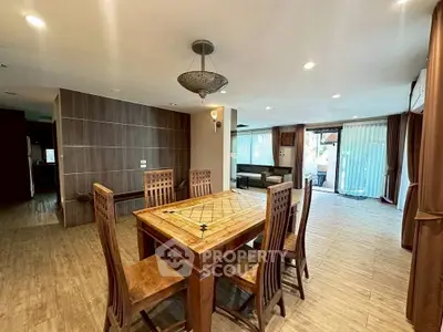 Spacious open-plan living and dining area with elegant wooden furniture and large windows.
