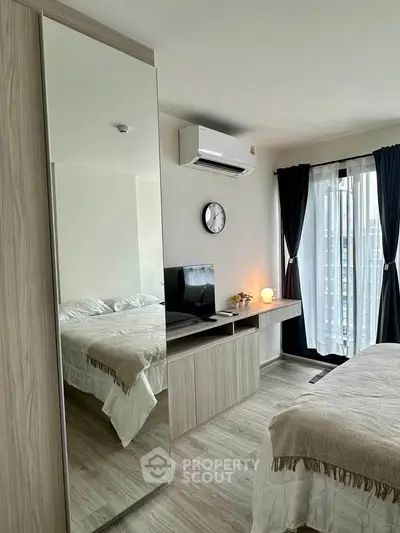 Modern bedroom with sleek design, featuring a large mirror, cozy bed, and natural light from floor-to-ceiling windows.