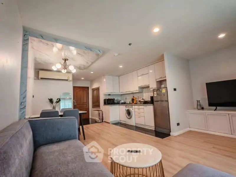 Modern open-plan living room with kitchen, featuring stylish furniture and appliances.