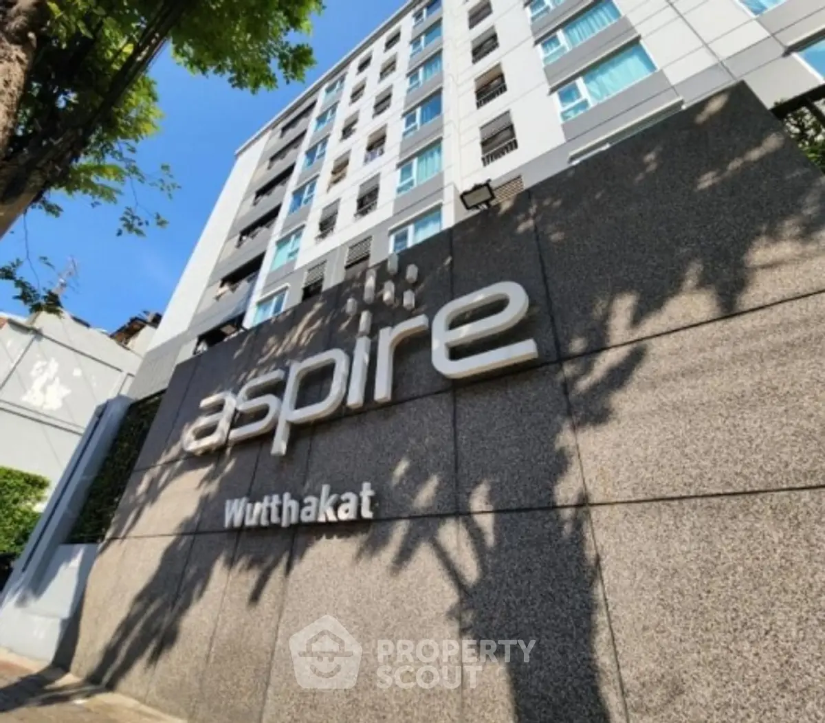 Modern high-rise building exterior with Aspire Wutthakat signage, showcasing urban living.