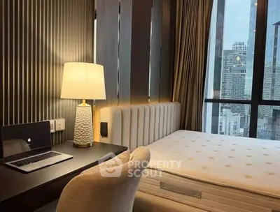 Modern bedroom with city view, featuring a cozy workspace and elegant decor.
