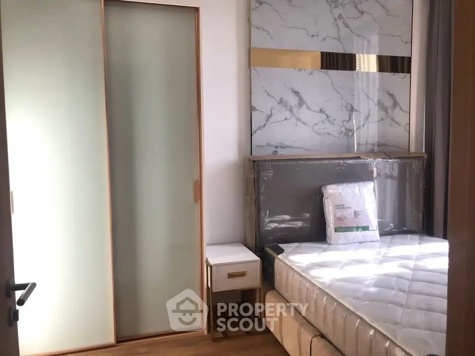 Modern bedroom with stylish marble accent wall and sliding closet doors.