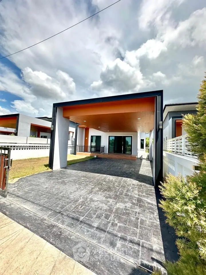 Modern single-story house with spacious driveway and contemporary design under a clear blue sky.