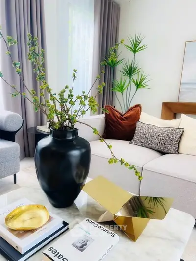 Stylish living room with modern decor, plush sofa, and elegant plant arrangement.
