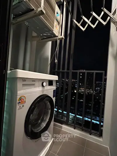 Compact balcony with washing machine and city night view, ideal for urban living.
