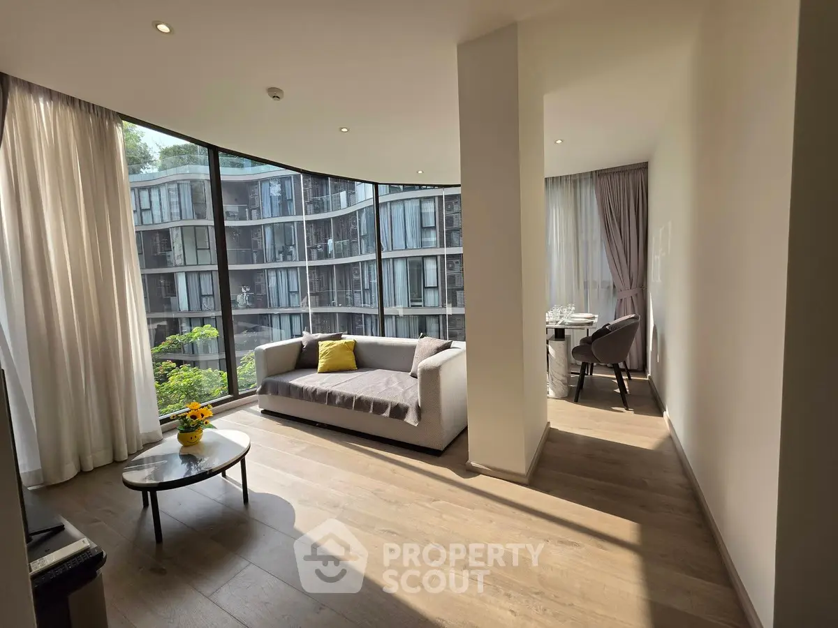 Modern living room with floor-to-ceiling windows and stylish furniture overlooking urban view.