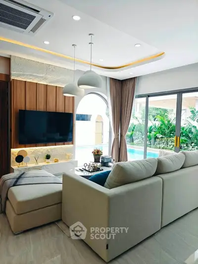 Luxurious living room with modern decor and pool view, featuring a cozy sectional sofa and elegant lighting.
