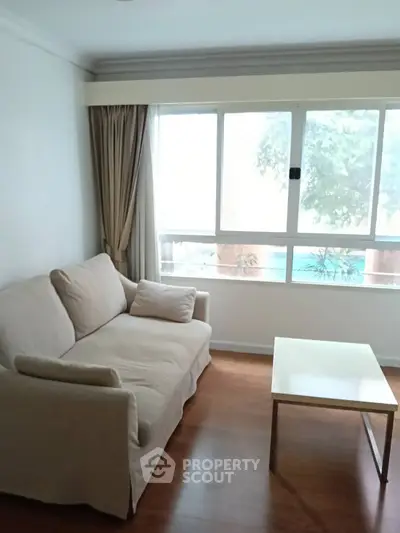 Cozy living room with large window and comfortable sofa, perfect for relaxation.
