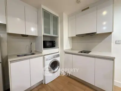 Modern compact kitchen with white cabinets and built-in washing machine