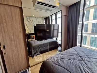 Modern bedroom with mirrored wardrobe and city view, featuring sleek design and natural light.