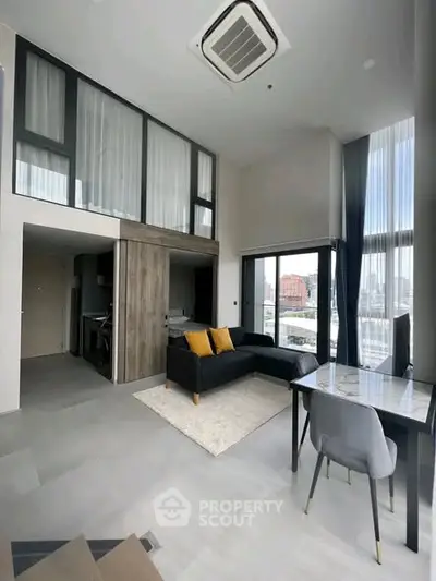 Modern loft apartment with high ceilings and large windows offering city views.