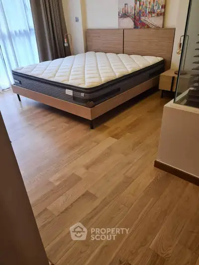 Spacious bedroom with modern wooden flooring and stylish bed setup.