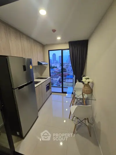 Modern kitchen with sleek design and city view from balcony, featuring stainless steel appliances and elegant decor.