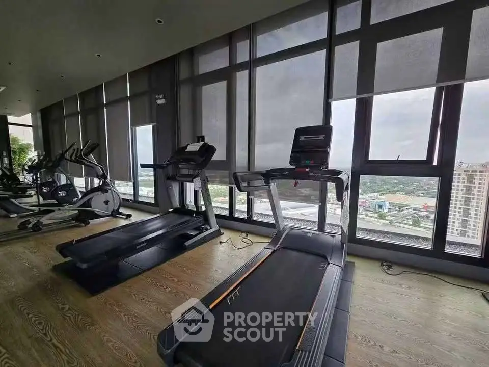 Modern gym with panoramic city views and state-of-the-art equipment in luxury high-rise building.