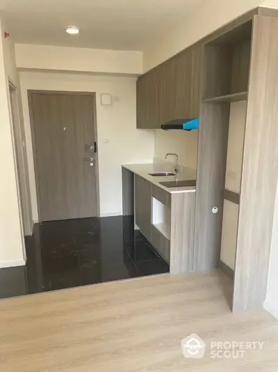 Modern compact kitchen with sleek wooden cabinets and black tile flooring