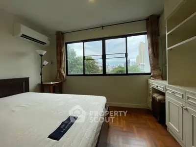 Spacious bedroom with large window and built-in storage, offering a serene city view.