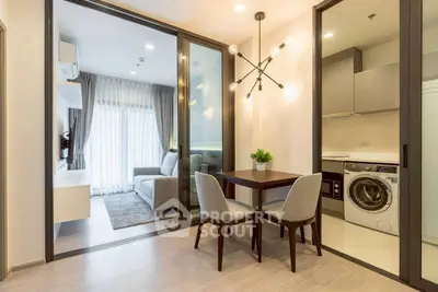 Modern open-plan living room with dining area and washing machine in stylish apartment.