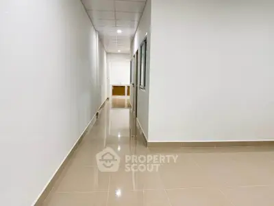 Spacious hallway with glossy tiled flooring and modern ceiling lights.