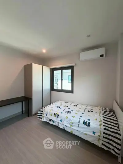 Cozy bedroom with modern furnishings and air conditioning, perfect for comfortable living.