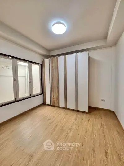 Spacious bedroom with wooden flooring and built-in wardrobe, ideal for modern living.