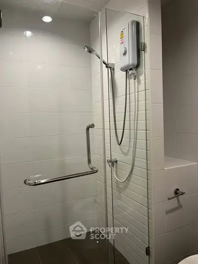 Modern bathroom with sleek shower and white tiles, featuring a convenient handrail and shower heater.