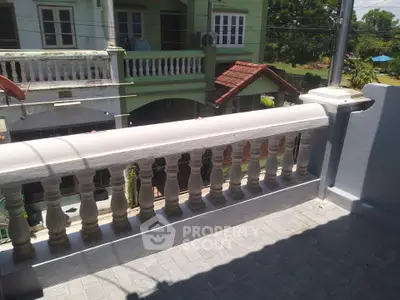 Charming balcony with classic balustrade overlooking a serene neighborhood view.