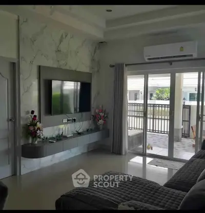 Modern living room with marble accent wall, large TV, and sliding glass doors leading to a patio.