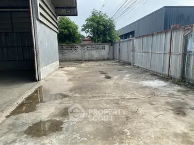 Spacious industrial outdoor area with concrete flooring and metal fencing, ideal for storage or parking.