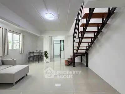 Modern minimalist living room with sleek staircase and dining area