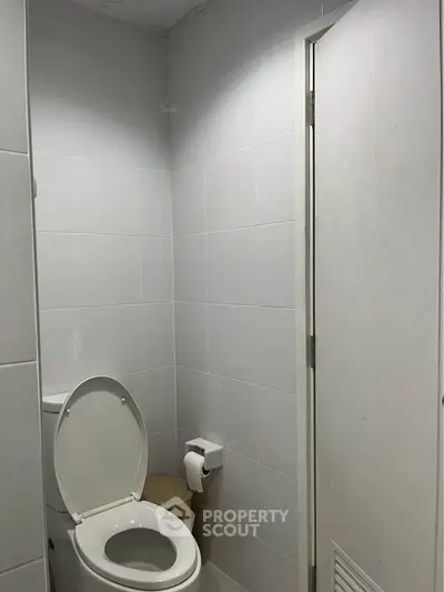 Modern bathroom with sleek white tiles and contemporary toilet design.