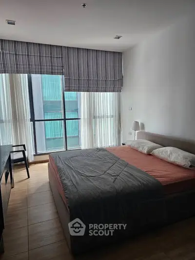 Modern bedroom with large windows and stylish decor in a high-rise apartment.