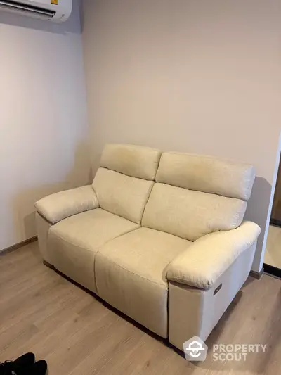 Cozy beige sofa in a modern living room with wooden flooring and neutral walls.