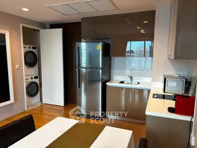 Modern kitchen with stainless steel appliances and in-unit laundry in stylish apartment.