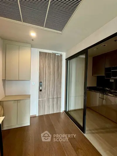 Modern apartment entrance with sleek kitchen and wooden flooring