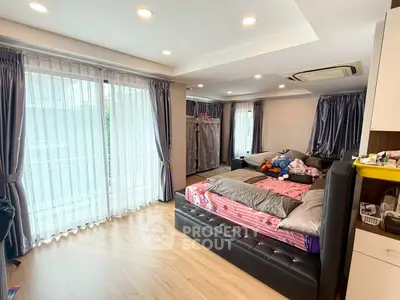 Spacious bedroom with large windows and modern decor, featuring a cozy bed and ample natural light.