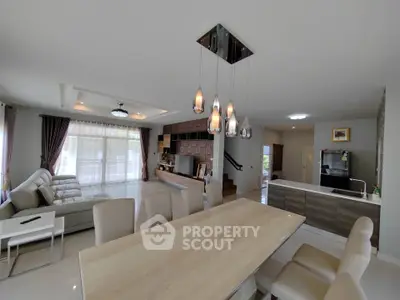 Spacious open-plan living and dining area with modern kitchen and elegant lighting.