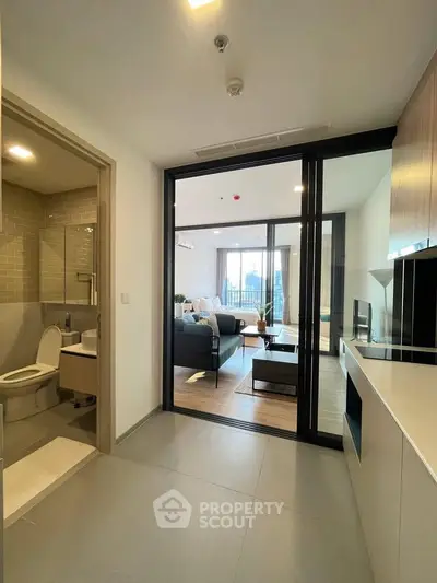 Modern apartment interior with open living room and bathroom, featuring sleek design and natural light.
