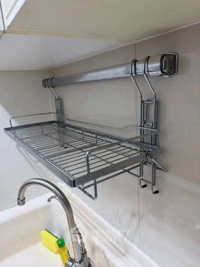 Modern kitchen with sleek metal dish rack above sink, showcasing efficient use of space.