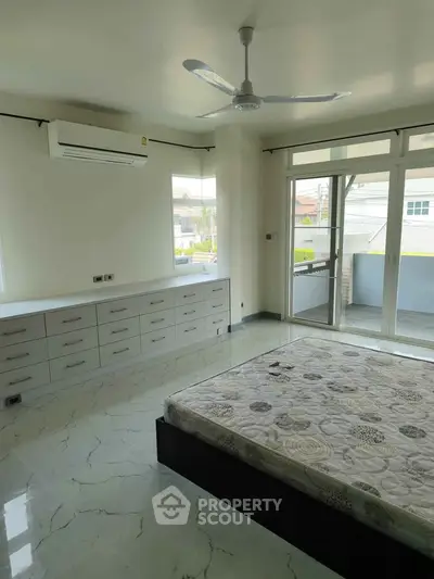 Spacious bedroom with large windows and balcony access, featuring modern design and ample natural light.